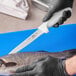 A person in gloves holding a Choice Flexible Fillet Knife over a fish.