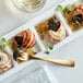A plate with a snail shell and three snails on a table.