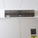 A Curtron stainless steel air curtain mounted above a door.