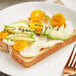 A slice of toast with Kewpie mayonnaise, avocado, and tomatoes on a plate with a fork.