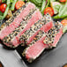 A plate of sushi-grade Ahi Tuna portions with sesame seeds and vegetables.