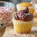 A cupcake with Peppermint Krunch Candy topping on a counter.