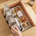 A hand holding a Lavex wine bottle in a cardboard box.