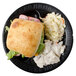 A sandwich and coleslaw on a Dart black foam plate.