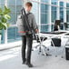 A man using a Hoover cordless backpack vacuum cleaner to clean an office.