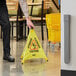A person holding a Lavex yellow Caution Wet Floor sign