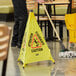 A man sweeping a floor with a yellow Lavex caution sign.