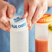 A person using a blue Choice silicone lid on a squeeze bottle of blue cheese.