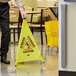 A person holding a Lavex yellow caution sign with black text.