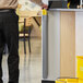A man using a Lavex wall-mounted wet floor sign to clean up a spill with a yellow bucket.