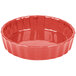 A red fluted china quiche dish with a white background.