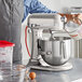 A man using a silver KitchenAid countertop mixer to mix a bowl of batter.