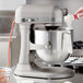 A woman using a KitchenAid silver countertop mixer to mix food.