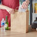 A person putting food in a Choice Natural Kraft paper bag.