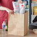 A hand holding a Choice Natural Kraft paper shopping bag filled with food.