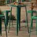 A Lancaster Table & Seating emerald green bar height table with green stool legs.