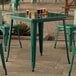 A Lancaster Table & Seating emerald green table with chairs and beer glasses on an outdoor patio.