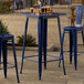 A Lancaster Table & Seating Sapphire bar height outdoor table with chairs on a patio.