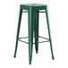 A green metal Lancaster Table & Seating outdoor backless barstool with legs.