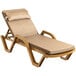 A tan Lancaster Table & Seating resin chaise lounge with a beige cushion and pillow on a white background.
