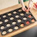 A person using a Sasa Demarle Flexipan Tatin tartlet mold to make apple tartlets.