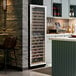 A tall, glass-door commercial wine cooler filled with wine bottles, situated in a modern kitchen or bar area.