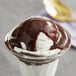 A Creamery Ave. hot fudge sundae with a scoop of ice cream and chocolate sauce in a glass cup.