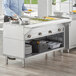 A man standing in a professional kitchen with a ServIt electric steam table on a large counter.