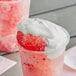 A cup of red liquid with whipped cream on top.
