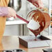 A person using a Choice silicone spoonula to pour chocolate into a pan.