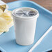 a white cup with a straw and chips on a blue tray