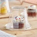 A cupcake with white frosting and sprinkles inside a Choice clear plastic container.