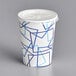 A white paper cold cup with a blue design and a lid with a flat straw slot.