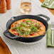 A Valor pre-seasoned cast iron skillet with a pan of pizza with cheese and basil on it.