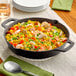 A Valor pre-seasoned cast iron skillet filled with rice, shrimp and vegetables on a table.