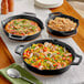 Three Valor cast iron skillets of food on a table.