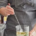 An American Metalcraft stainless steel bar spoon with a red knob being used to stir a drink.