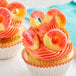 A cupcake with pink frosting and Albanese Gummi Peach Rings on top.