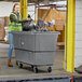 A woman in a green reflective vest pushing a black bag into a large grey Lavex cube truck.