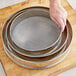 A hand holding a Choice 16" stainless steel sieve.