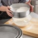 A person using a Choice stainless steel sieve to sift flour into a bowl.