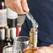 A person using an Acopa waiter's corkscrew to open a bottle of wine.