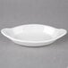 A white Hall China oval rarebit dish with a handle.