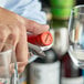 A person using an Acopa Flex Waiter's Corkscrew with a dark wood handle to open a bottle of wine on a table.