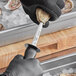 a hand in a black glove holding a metal object