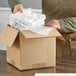 A person opening a box of Lavex white tissue paper sheets.