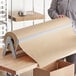 A person holding a roll of Lavex natural kraft void fill packing paper