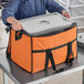 A woman holding a Choice orange insulated cooler bag.
