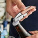 A person using an Acopa Flex waiter's corkscrew with a rosewood handle to open a bottle on a table in a cocktail bar.