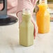 A person holding a 10 oz. square clear juice bottle.